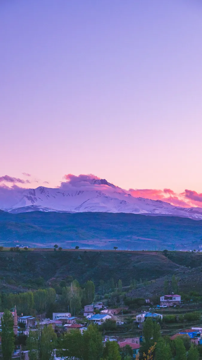 Gün batımında pembe gökyüzü altında Erciyes ve eteklerindeki yeşil vadi