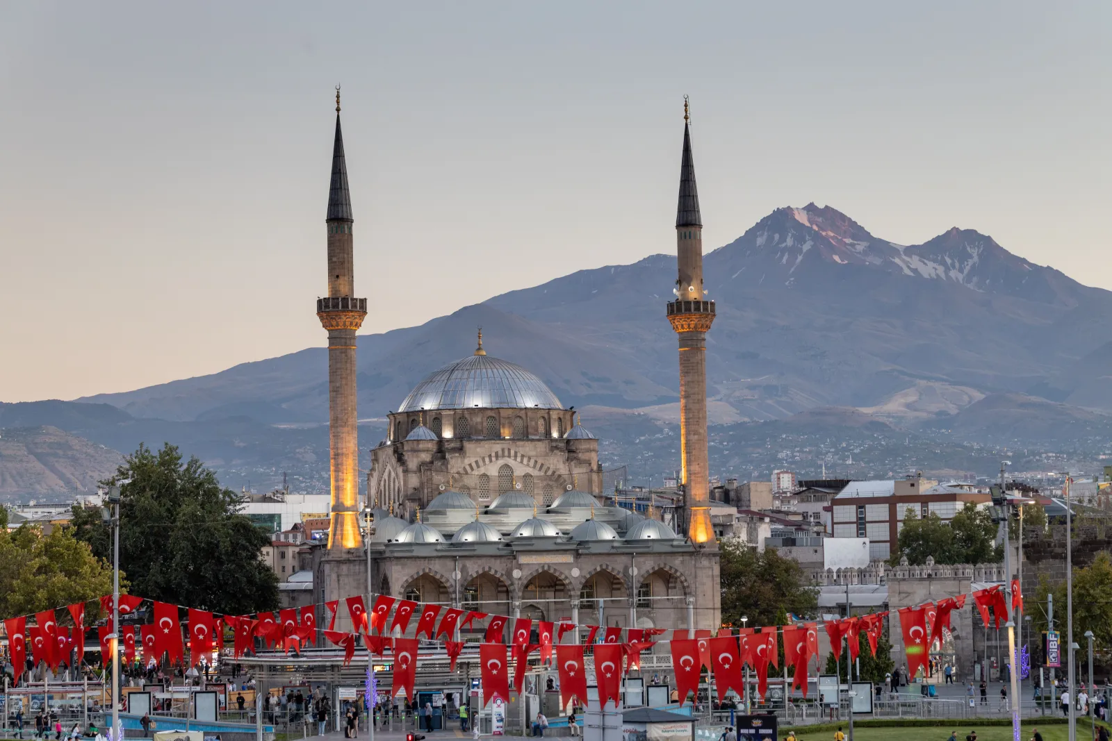 Kayseri'de bayraklarla süslü meydandaki bir cami ve arkasında Erciyes Dağı