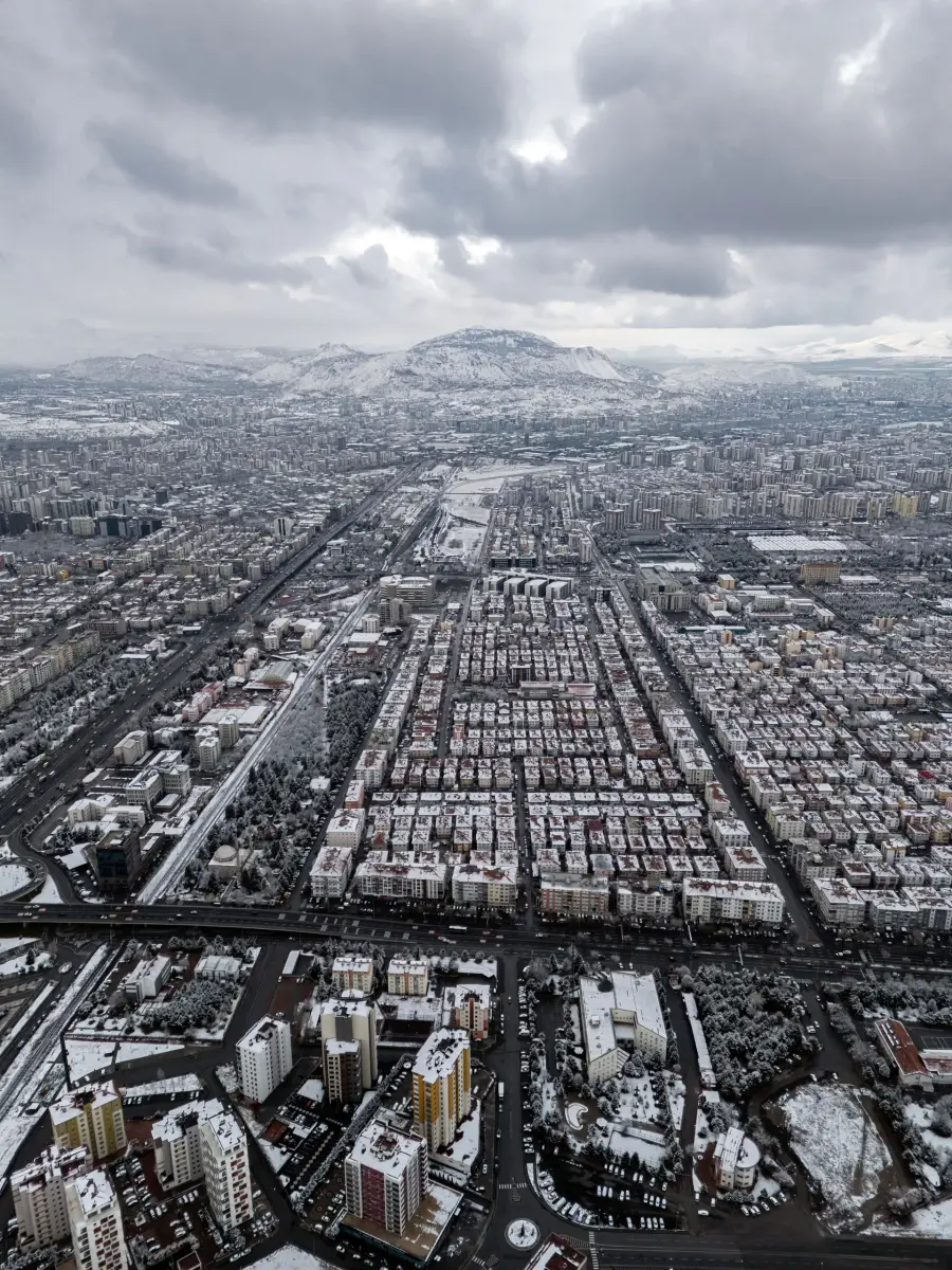 Karla kaplı Kayseri şehrinin havadan görünümü, arkada karlı dağlar ve bulutlu gökyüzü