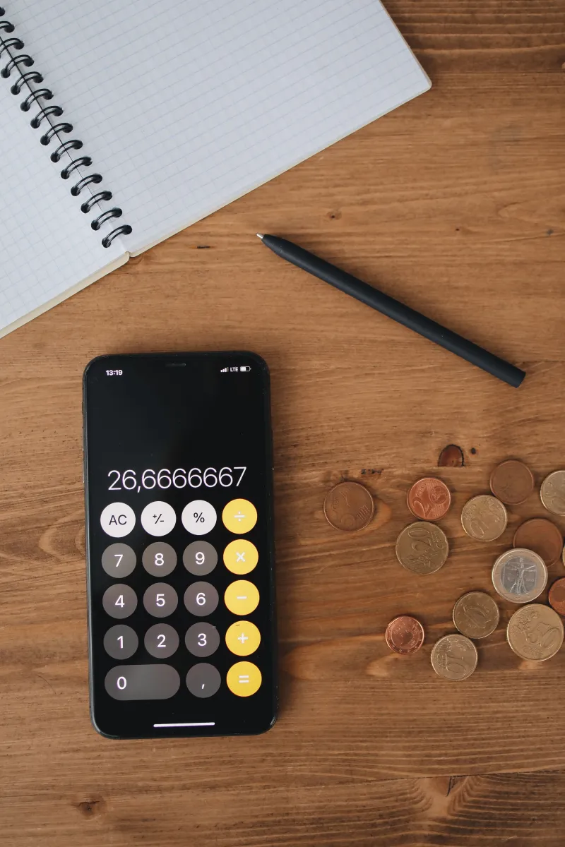 Hesap makinesi açık bir telefon, bozuk paralar ve defter